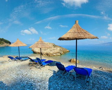 Yaz sabah Pulebardha plaj şezlong, strawy şemsiye ve çakıl (Saranda, Arnavutluk).