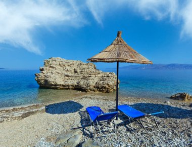 Yaz sabah Pulebardha plaj şezlong ve strawy tente (Saranda, Arnavutluk).