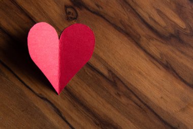 close up of small heart shaped cut out on a wooden table with a beautiful texture