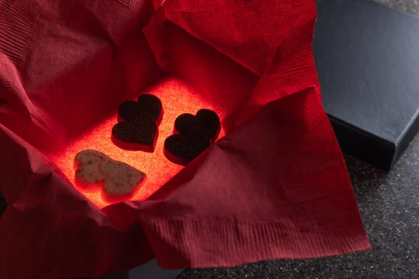 Heart shaped chocolates in a box with a light inside for a glow and a red napkin for color