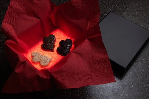 Heart shaped chocolates in a box with a light inside for a glow and a red napkin for color