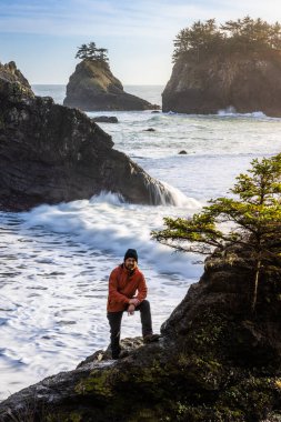 Man sitting on a rock enjoying the amazing view of the sea and sea stacks in this beautiful spot on the Oregon coast