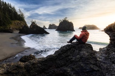 Man sitting on a rock enjoying the amazing view of the sea and sea stacks in this beautiful spot on the Oregon coast
