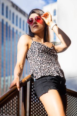 Güzel bir kadın mavi ışıklı gözlük takıyor ve telefonunu içeride kullanıyor.