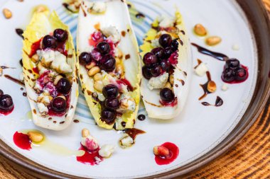 Taze Belçika hindiba dalışı tekneleriyle yapılmış vejetaryen aperatifleri kızarmış çam fıstığı, bleu peyniri, taze yaban mersini ve balzamik çiselemeli taze zeytin yağı ile doldurulmuş..