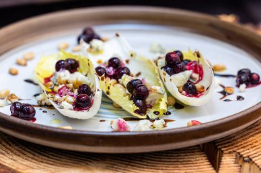 Taze Belçika hindiba dalışı tekneleriyle yapılmış vejetaryen aperatifleri kızarmış çam fıstığı, bleu peyniri, taze yaban mersini ve balzamik çiselemeli taze zeytin yağı ile doldurulmuş..