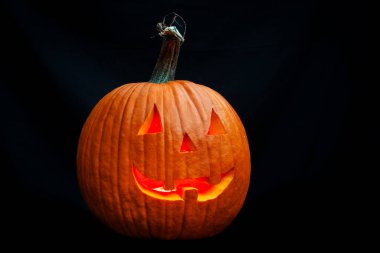 Siyah bir arkaplanda izole edilmiş gülümseyen bir Cadılar Bayramı balkabağına yaklaş