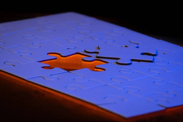 close up of a blank puzzle with a blue and orange light as a concept.
