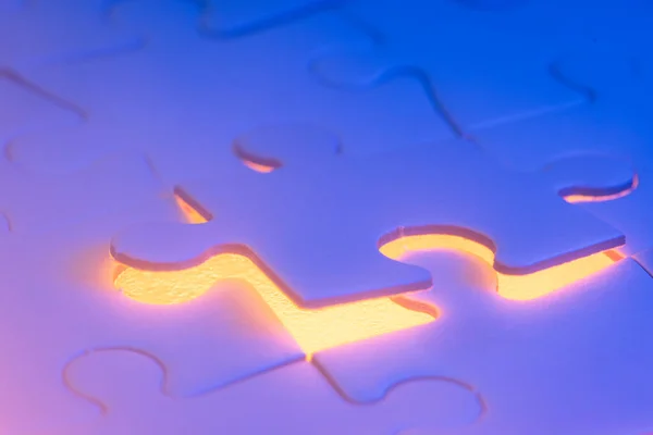 close up of a blank puzzle with a blue and orange light as a concept.