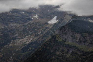 Buzullar, fırtınalı bulutlar ve sonbahar renkleriyle Buzul Ulusal Parkı 'ndaki sarp dağlara tutunur.