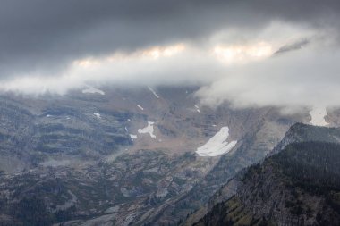 Buzullar, fırtınalı bulutlar ve sonbahar renkleriyle Buzul Ulusal Parkı 'ndaki sarp dağlara tutunur.
