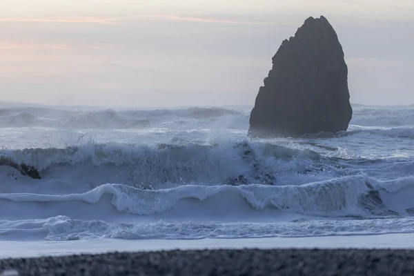 大きな岩が海にあり 波がそれに衝突する シーンは穏やかで平和で 岩は水の力に対して背が高く強く立っています — ストック写真