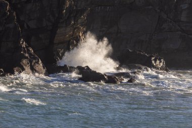 Okyanus sakin ve dalgalar küçük. Kayalar suda ve su mavi.