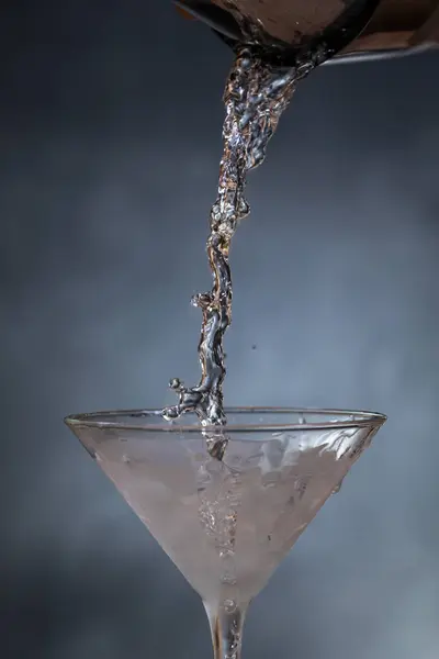 Tiro Ação Derramar Gin Resfriado Copo Martini Sobre Fundo Azulado — Fotografia de Stock