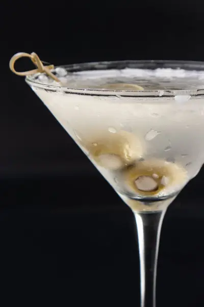 Chilled vodka martini with bleu cheese stuffed olives isolated over a black background