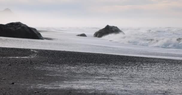 一个岩石的海滩 天空灰蒙蒙 身后波涛汹涌 海滩上空无一人 岩石散落在沙滩上 风平浪静 风平浪静 — 图库视频影像