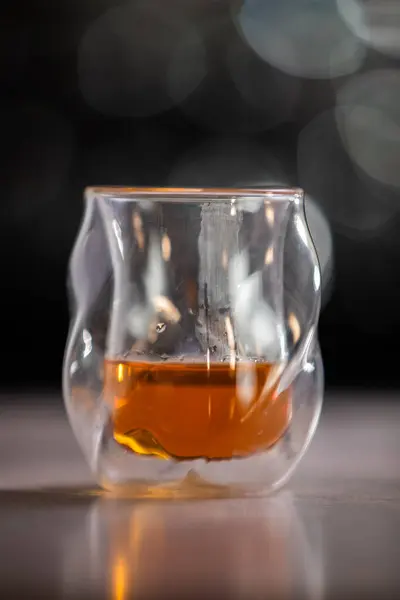 テーブルの上に一杯のアルコールが置かれている ガラスは半分満たされており 内部の液体は茶色です リラックスと楽しみの概念は 酒のガラスがしばしば社会化に関連しているため ストックフォト