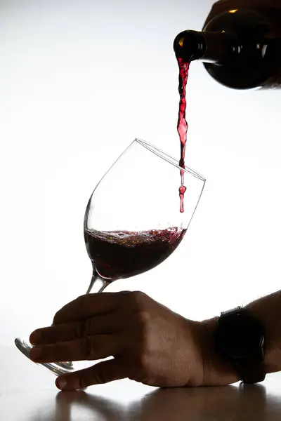 白い背景にグラスに赤ワインを注ぐアクションショット ロイヤリティフリーのストック写真