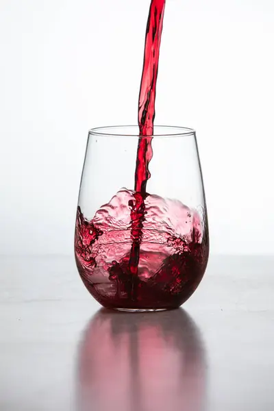 Action Shot Gieten Rode Wijn Een Glas Een Witte Achtergrond Rechtenvrije Stockafbeeldingen