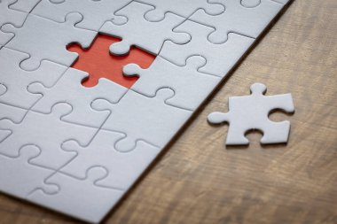 Boş bir yapboz, bütün parçaların yanında bir parça eksik ve son parçanın ait olduğu yerde kırmızı bir yer var. Sorun çözme kavramı.