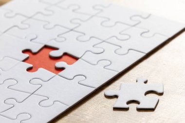 Boş bir yapboz, bütün parçaların yanında bir parça eksik ve son parçanın ait olduğu yerde kırmızı bir yer var. Sorun çözme kavramı.