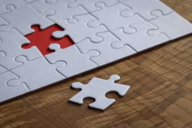 Boş bir yapboz, bütün parçaların yanında bir parça eksik ve son parçanın ait olduğu yerde kırmızı bir yer var. Sorun çözme kavramı.