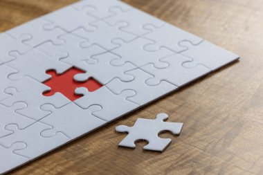 Boş bir yapboz, bütün parçaların yanında bir parça eksik ve son parçanın ait olduğu yerde kırmızı bir yer var. Sorun çözme kavramı.