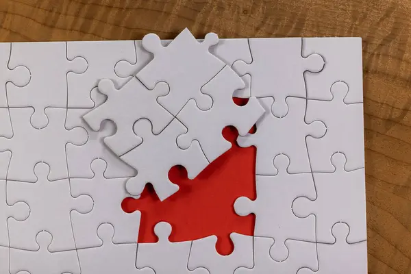 Blank puzzle with one missing piece next to the whole with a red placer where the last piece belongs. Concept for problem solving.