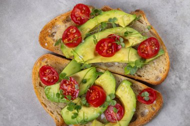 Üstünde avokado ve domates olan bir dilim kızarmış ekşi ekmek.