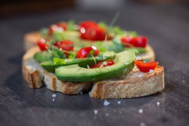 Üstünde avokado ve domates olan bir dilim kızarmış ekşi ekmek.