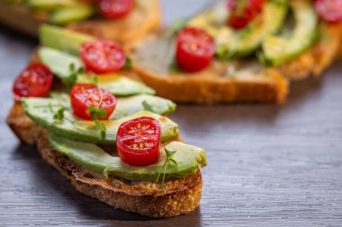 Üstünde avokado ve domates olan bir dilim kızarmış ekşi ekmek.