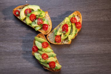 Üstünde avokado ve domates olan bir dilim kızarmış ekşi ekmek.