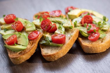 Üstünde avokado ve domates olan bir dilim kızarmış ekşi ekmek.