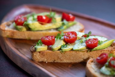 Üstünde avokado ve domates olan bir dilim kızarmış ekşi ekmek.