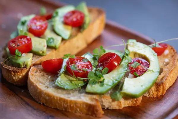 stock image A slice of toasted sour dough bread with avocado and tomato on top