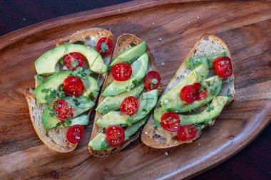 Üstünde avokado ve domates olan bir dilim kızarmış ekşi ekmek.