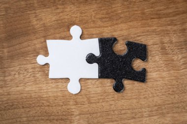 Yin yang ya da karşıtlık kavramına mükemmel uyan bir sırt ve beyaz yapboz parçası yapboz parçaları ahşap bir masanın üzerinde.