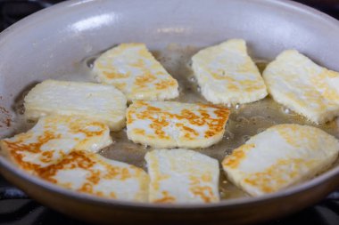 Bir tava halloumi peyniri altın kahverengi bir kabukla gösterilir. Sıcak tereyağında pişirmek. Yemek lezzetli ve davetkar görünüyor.