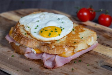 Croque Madame veya ızgara peynirli jambon ve yumurtalı ahşap kesim tahtası. Sandviç kızartılmış ve cıvık sarısı var.