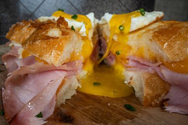 Croque Madame veya ızgara peynirli jambon ve yumurtalı ahşap kesim tahtası. Sandviç kızartılmış ve cıvık sarısı var.