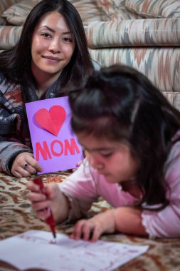 Küçük bir kız annesi için kart çekiyor. Karta 
