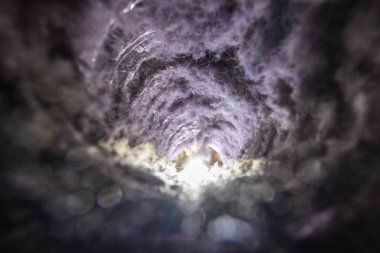 Kurutma makinesinin içindeki tiftik birikintisinin yakın plan görüntüsü, ev içinde yangın tehlikesini vurguluyor. Fotoğrafta havalandırma borusunda birikmiş toz, lif ve enkaz birikintileri görülüyor. Düzenli bakım ve temizliğin önemini vurguluyor..