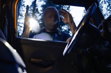 Maskeli bir şahıs, arabanın camından içeri bakarken el feneri tutuyor. Bu da bir araç soygunu ya da hırsızlık girişimi olduğunu gösteriyor..