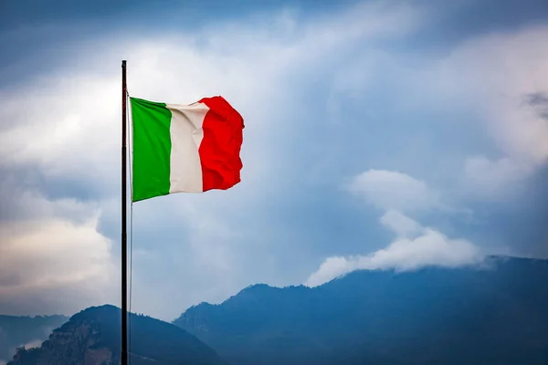 意大利国旗在天空和山丘的背景下飘扬 免版税图库图片
