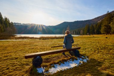 Bir kadın oturuyor ve göle bakıyor.
