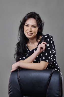 Gri bir arka planda farklı pozlar veren esmer bir iş kadınının portresi..