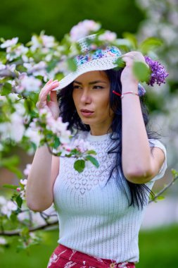 Çiçekli bir elma bahçesinde güzel esmer bir kadının portresi.