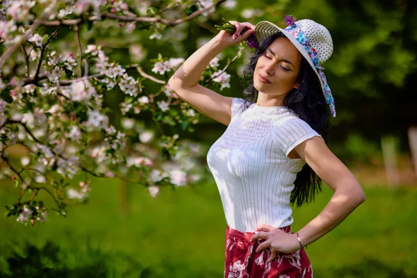 在盛开的苹果园里一个美丽的黑发女人的画像 — 图库照片