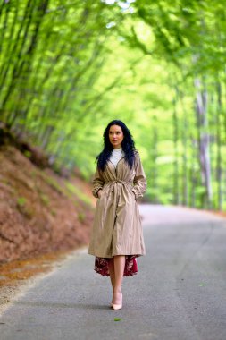 Ağaçların arasındaki yolda esmer bir kadının portresi.