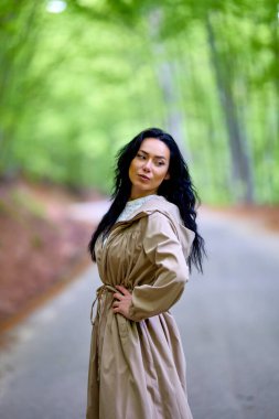 Ağaçların arasındaki yolda esmer bir kadının portresi.